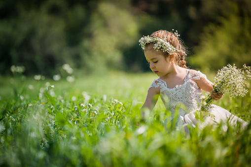Happy little girl walking in a field with hay bales on a summer day