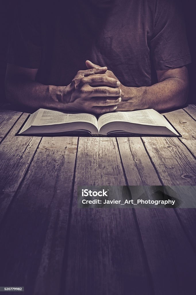Man praying on a wooden table with an open Bible Man praying on a wooden table with an open Bible. Praying Stock Photo