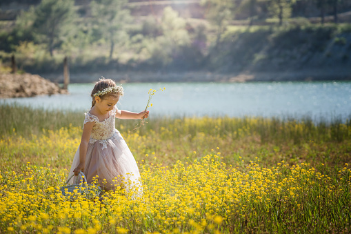 sweet baby girl outdoors with  basket of flowers,nature background