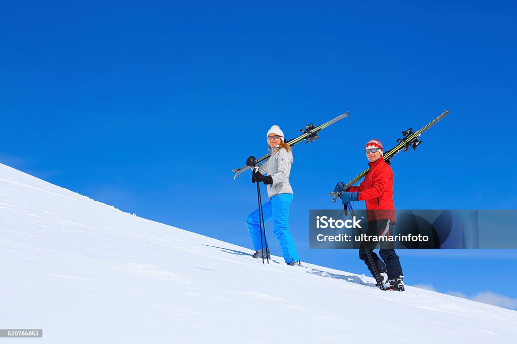 Winter sport  friends men and women snow skiers carrying skis Winter sport - alpine skiing. Best friends men and women, snow skiers carrying skis, enjoying on sunny ski resorts. Beautiful blue sky in the background. High mountain snowy landscape. Livigno mountain range, Alps. It is located in the Italiy. Shot with Canon 5DMarkIII, developed from RAW, Adobe RGB color profile. Shallow DOF for soft background. Adult Stock Photo