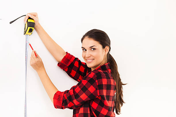 istock Young woman measuring the wall 520787937