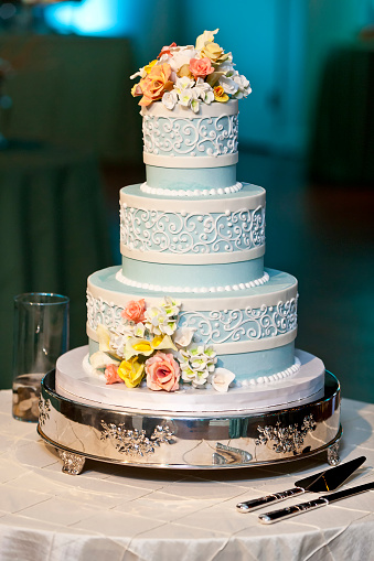 three tiered blue and white wedding cake with confectionery roses