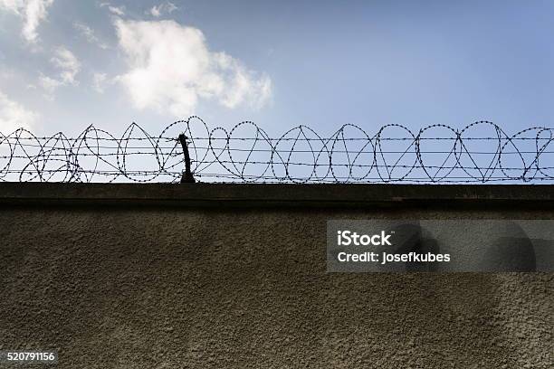 Prison Wall Barbed Wire Fence With Blue Sky Background Stock Photo - Download Image Now