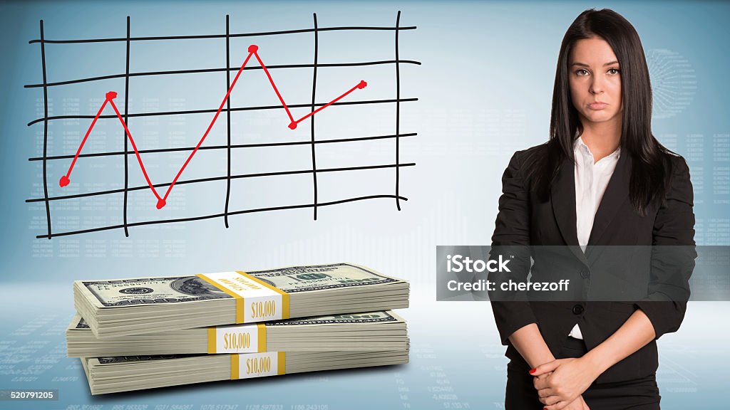 Upset businesswoman looking at camera with packs dollars Upset businesswoman looking at camera with packs dollars. Schedule of price increases in background Adult Stock Photo