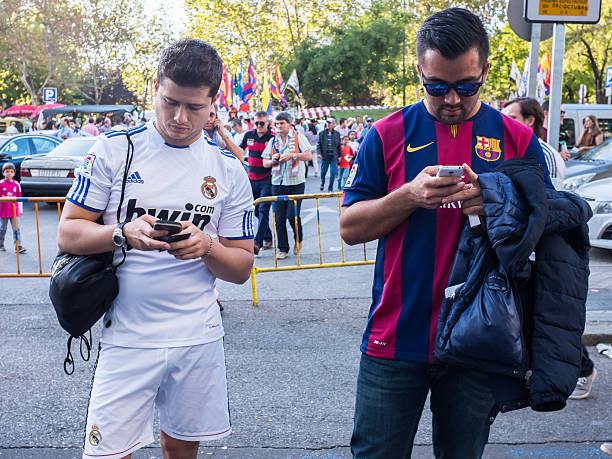 Two friends supporting Real Madrid and Barcelona watching their Smartphones stock photo