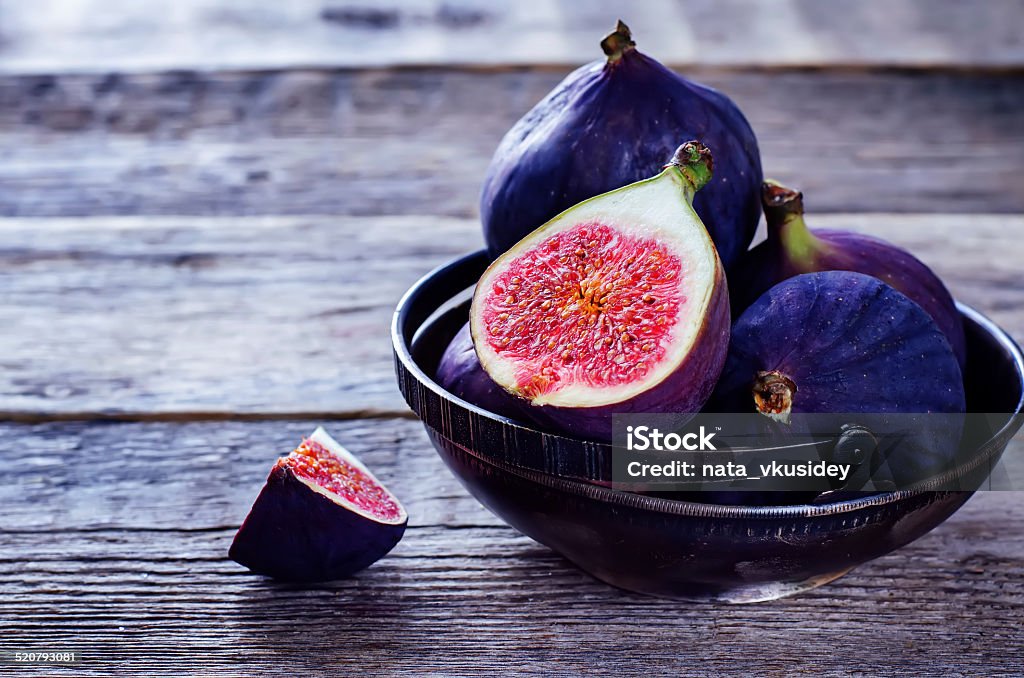 figs figs on a dark wood background. tinting. selective focus on the front figs slice in the bowl Berry Fruit Stock Photo