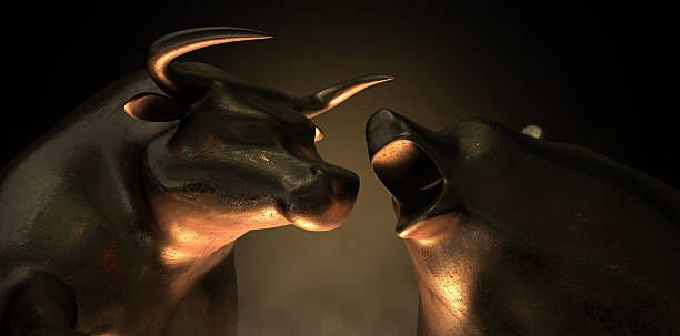 Bull And Bear Market Statues An abstract closeup of two gold cast statuettes depicting a stylized bull and a bear in dramatic contrasting light representing a financial market trends on an isolated dark background bull market stock pictures, royalty-free photos & images