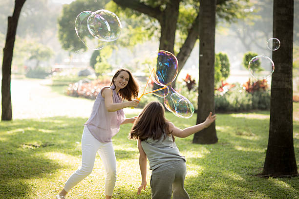 istock Happy mother and her daughter playing soap bubbles in park. 520797524