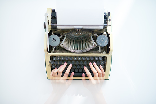 Transparent female hand typing text on typewriter 