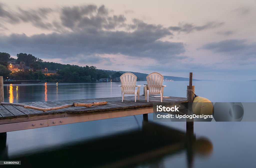 Idyllic Lake Seneca Two chairs sitting on a jetty at dusk, form a tranquil and idyllic scene at Lake Seneca, a popular vacation destination and located in the famous Finger Lakes region in New YorkState. Finger Lakes Stock Photo