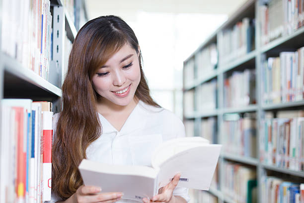 istock asian girl student with book in modern library 520801356