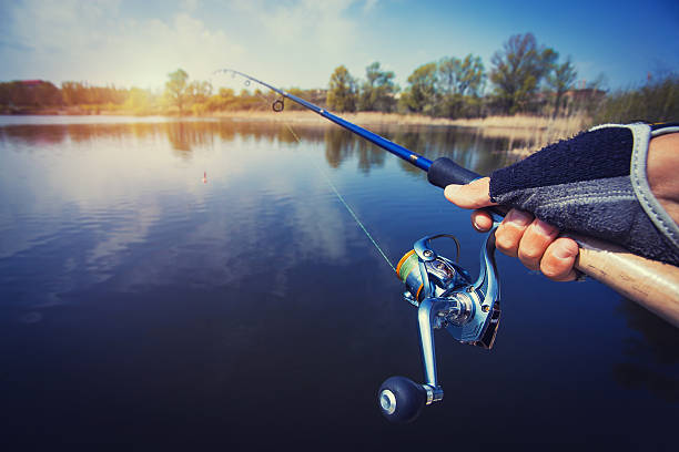istock hand with spinning and reel on the evening summer lake 520802870