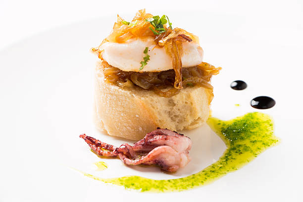 Tapa of squid with caramelized onion Squid with caramelized onion, parsley a nd some drops of vinegar syrup over a bread slice, called in the Basque Country as Pelayo squids french basque country photos stock pictures, royalty-free photos & images
