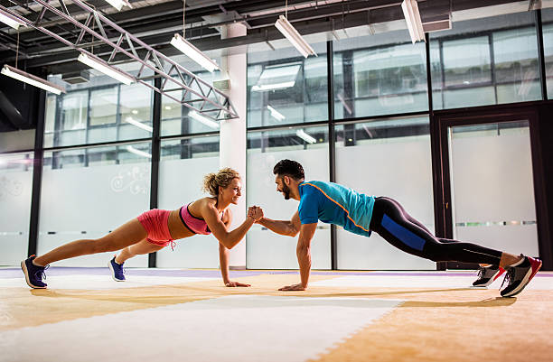 uśmiechnięta para robienie pompek razem w siłowni. - exercising men push ups muscular build zdjęcia i obrazy z banku zdjęć