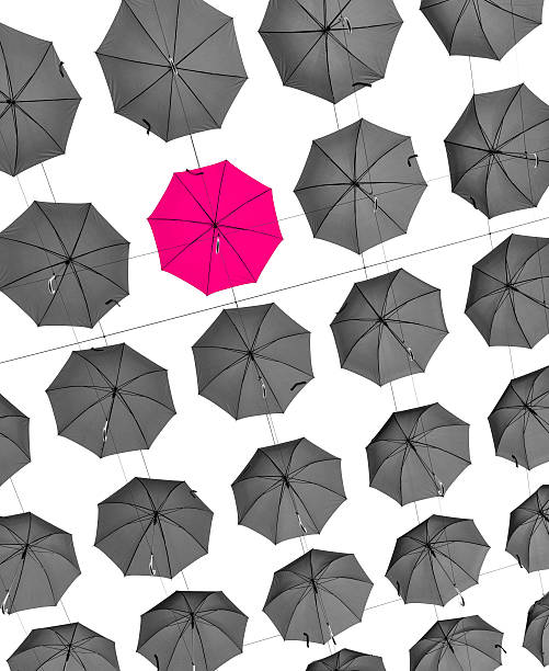 istock Uniqueness business concept, one pink umbrella between many grey ones 520809651