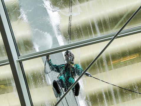 Singapore, Singapore - February 15, 2011: unidentified men at work, pressure washing the glass roof of a shopping center on February 15th 2011 in Singapore, Singapore