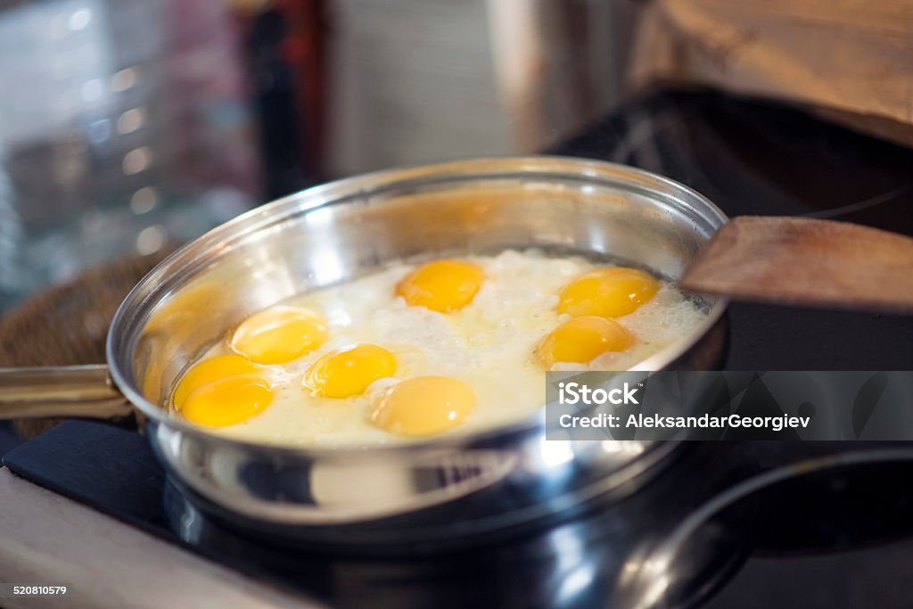Making Breakfast - Cooking Fried Eggs in The Pan Making Breakfast - Cooking Fried Eggs in The Pan. Black Color Stock Photo