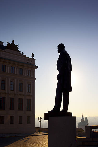 Prague, Czech Republic - August 17, 2019: Gray living statue of a man in the hat against historical facades of Old City Square in Prague, Czech Republic.