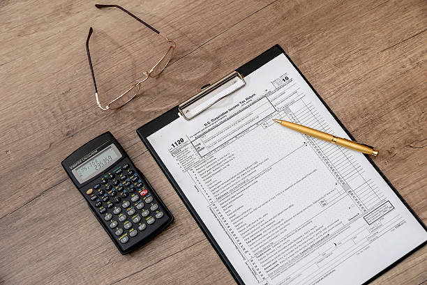 istock US 1120 tax form, pen, calclator on desk 520835082