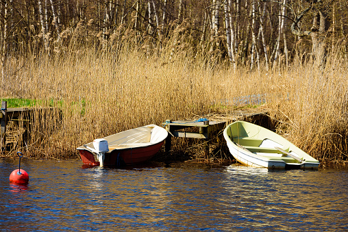 Two small open plastic boats moored at a wooden pier in the reeds.