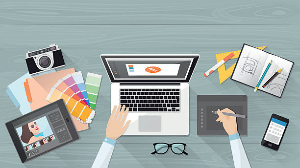 Designer working at desk Professional creative graphic designer working at office desk, he is designing a vector illustration using a laptop working designs stock illustrations
