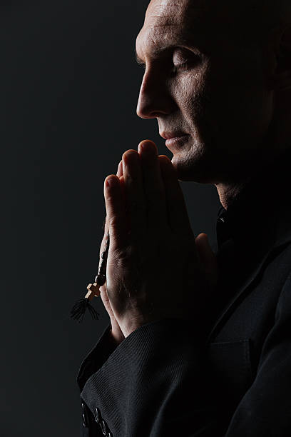 istock Man with eyes closed holding rosary and praying 520839954