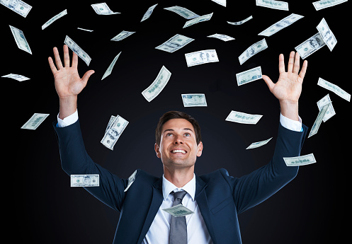 Studio shot of a handsome young businessman surrounded by falling money