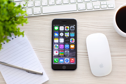 Alushta, Russia - October 25, 2014: New phone iPhone 6 Space Gray with apps on screen lies on the table. iPhone 6 was created and developed by the Apple inc.