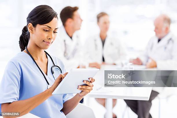 Nurse Using Digital Tablet With Medical Team Discussing In Boardroom Stock Photo - Download Image Now