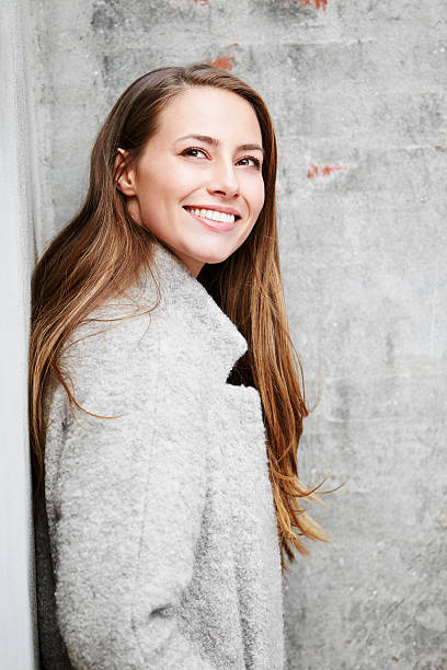 istock Beautiful woman in gray coat against wall 520842256