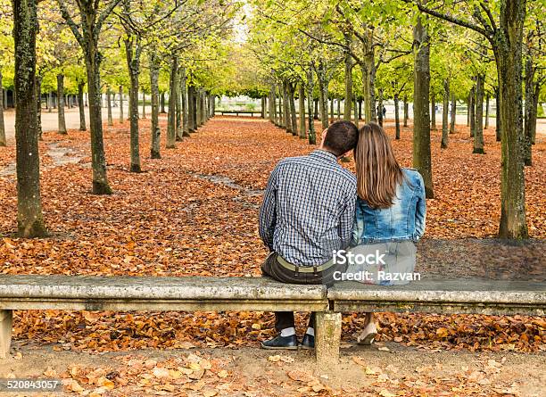 Young Couple Sitting On A Bench Stock Photo - Download Image Now - Adult, Adults Only, Alley
