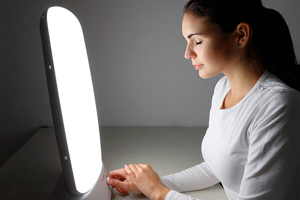 Young woman administering a light therapy agains winter depression stock photo