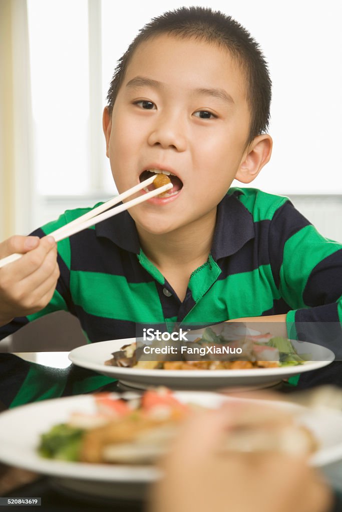 Boy (8-9) eating with chopsticks, smiling, portrait 45-49 Years Stock Photo