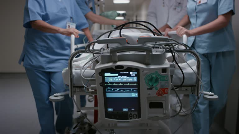 Medium dolly shot of the monitor on the gurney as the patient is being transported to the operating room by the medical team.