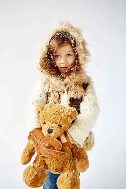 Photo of little serious girl holding her favorite teddy-bear