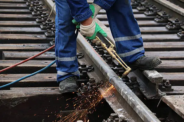 Welder using cutting torch to cut a rail