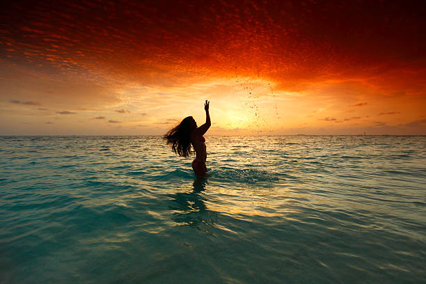 istock Woman splashing in sea on sunset 520864599