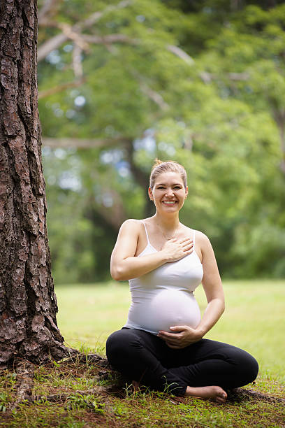 임산부 찌는 요가 명상하기 나무 공원 - spirituality hand on heart meditating women 뉴스 사진 이미지