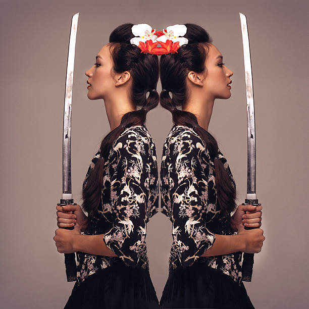 She's a warrior Mirrored studio shot of an attractive young woman holding a samurai sword geisha costume stock pictures, royalty-free photos & images