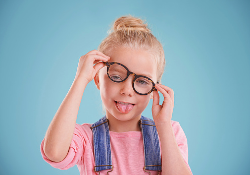 Studio shot of a little girl wearing hipster glasses on a blue background