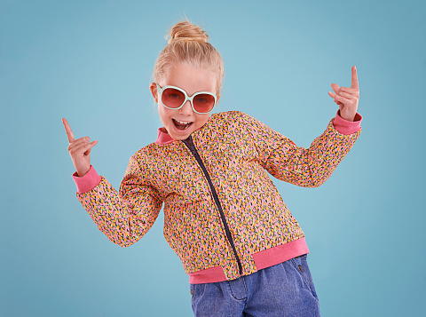 Studio shot of a little girl wearing funky glasses on a blue background