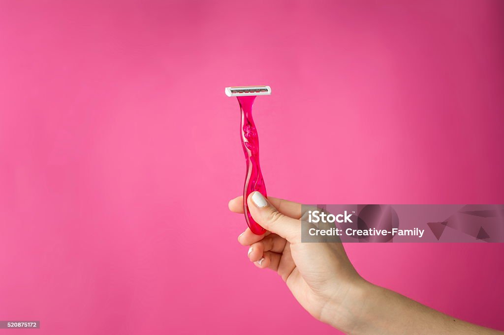 Red shaver in woman hands Red shaver in woman hands against pink background Razor Stock Photo