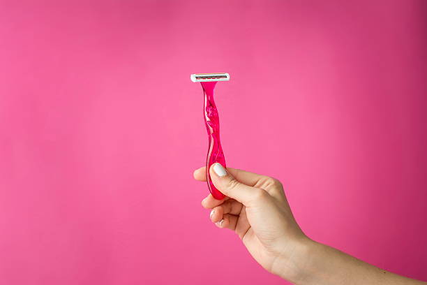 Red shaver in woman hands Red shaver in woman hands against pink background blade stock pictures, royalty-free photos & images