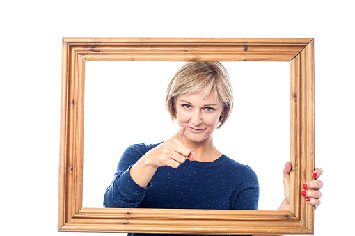 Woman pointing at the camera from a wooden frame