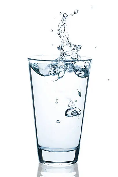 Photo of Water glass with splashing water and drops