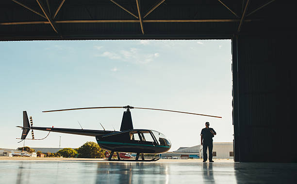 istock Pilot with a helicopter in airplane hangar 520880518