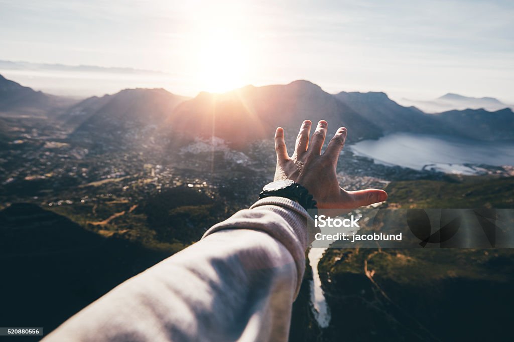 Hand of a man reaching out the beautiful landscape Hand of a man reaching out the beautiful landscape. POV shot of human hand on a sunny day. Reaching Stock Photo