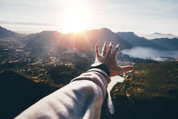 Hand of a man reaching out the beautiful landscape Hand of a man reaching out the beautiful landscape. POV shot of human hand on a sunny day. reaching stock pictures, royalty-free photos & images