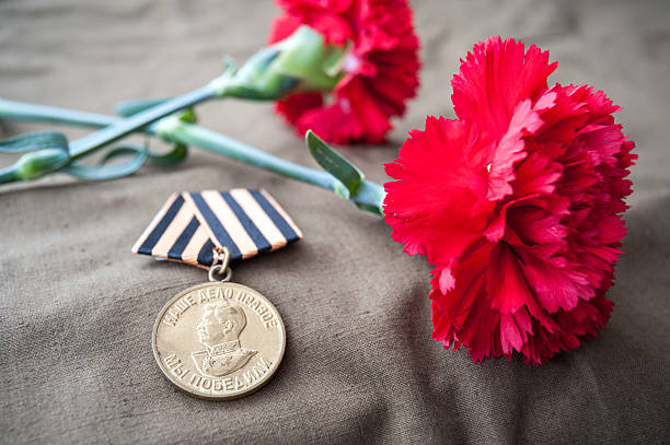 Medal For Victory over Germany in the Great Patriotic War of 1941-1945 and two red carnations. Still life dedicated to Victory Day. 9 May.