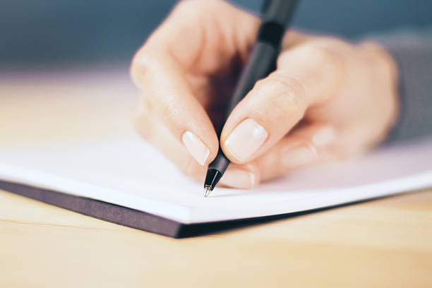 istock Girl hand with pen and notebook on wooden table 520886684